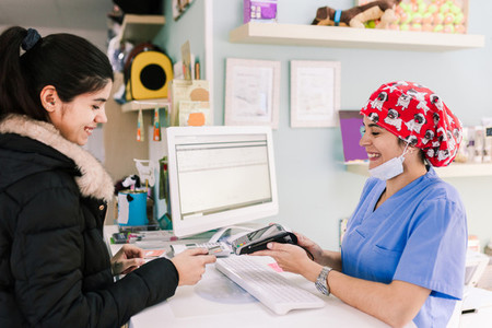 Young woman paying in a veterinary with credit card