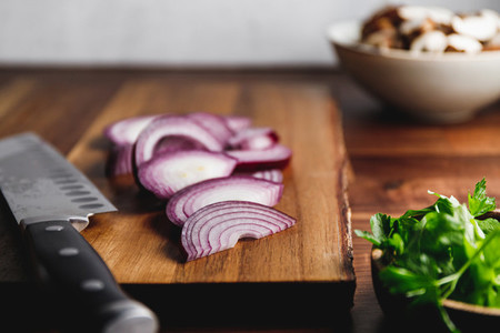 Close up of wooden cutting board  knife and onion on a kitchen table  Cooking concept