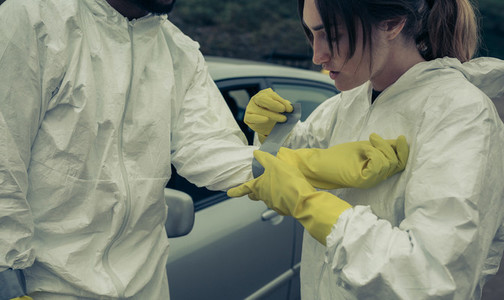 Woman taping bacteriological protective gloves to a man