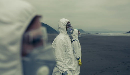 People with bacteriological protection suits looking at the sea