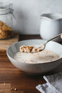 Hand holds a spoon with baked granola and almond milk  Healthy vegetarian breakfast
