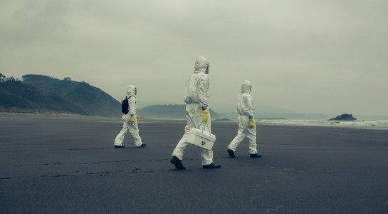People with bacteriological protection suits walking on the beach