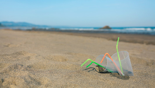 Beach with plastic cups and straws