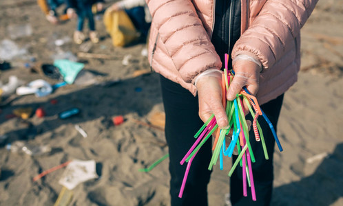 Woman showing handful of straws collected on the beach