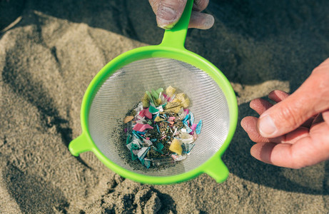 Colander with microplastics on the beach
