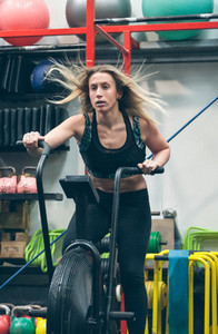 Sportswoman doing air bike at the gym