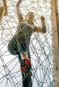 Participant in obstacle course climbing net