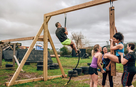Participants in obstacle course doing pegboard and rope