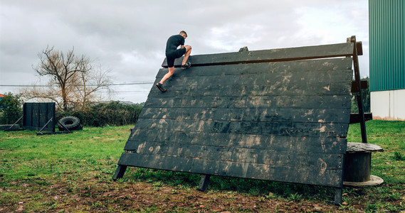 Participant in obstacle course climbing pyramid obstacle