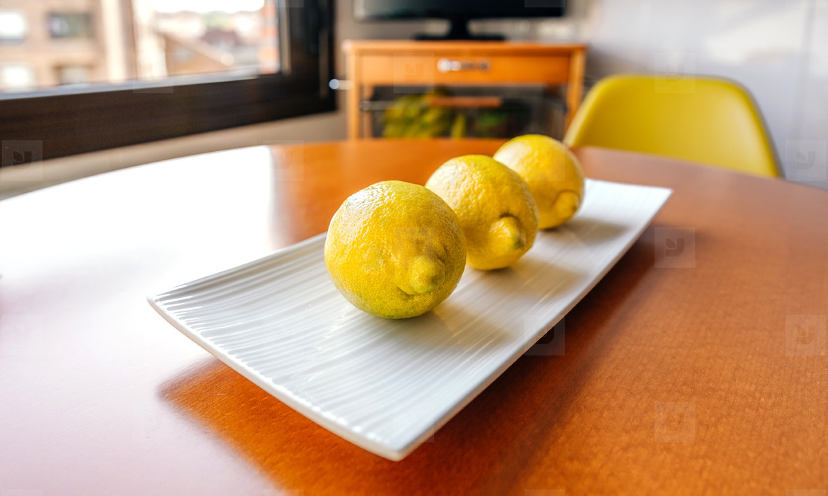 Three lemons on a white plate