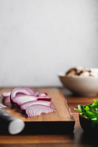 Close up of wooden cutting board  knife and onion on a kitchen table  Cooking concept