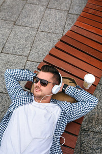 Man with headphones lying on a bench