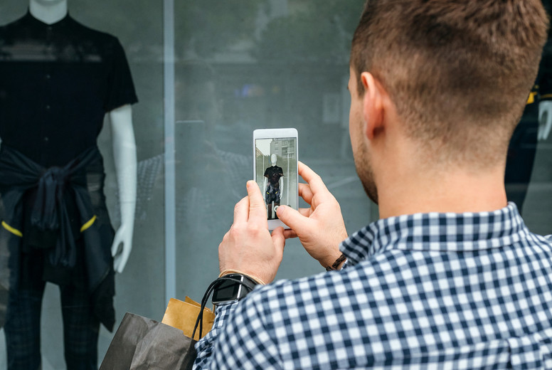 Man taking a photo of a shop window of a fashion store
