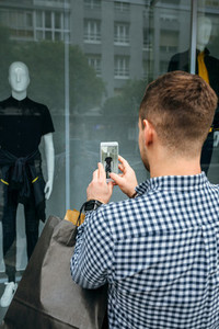 Man taking a photo of a shop window of a fashion store