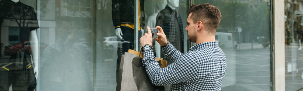 Man taking a photo of a shop window of a fashion store
