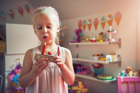Girl blowing to candle on toy cake
