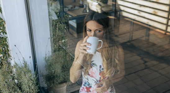 Woman behind the window drinking coffee