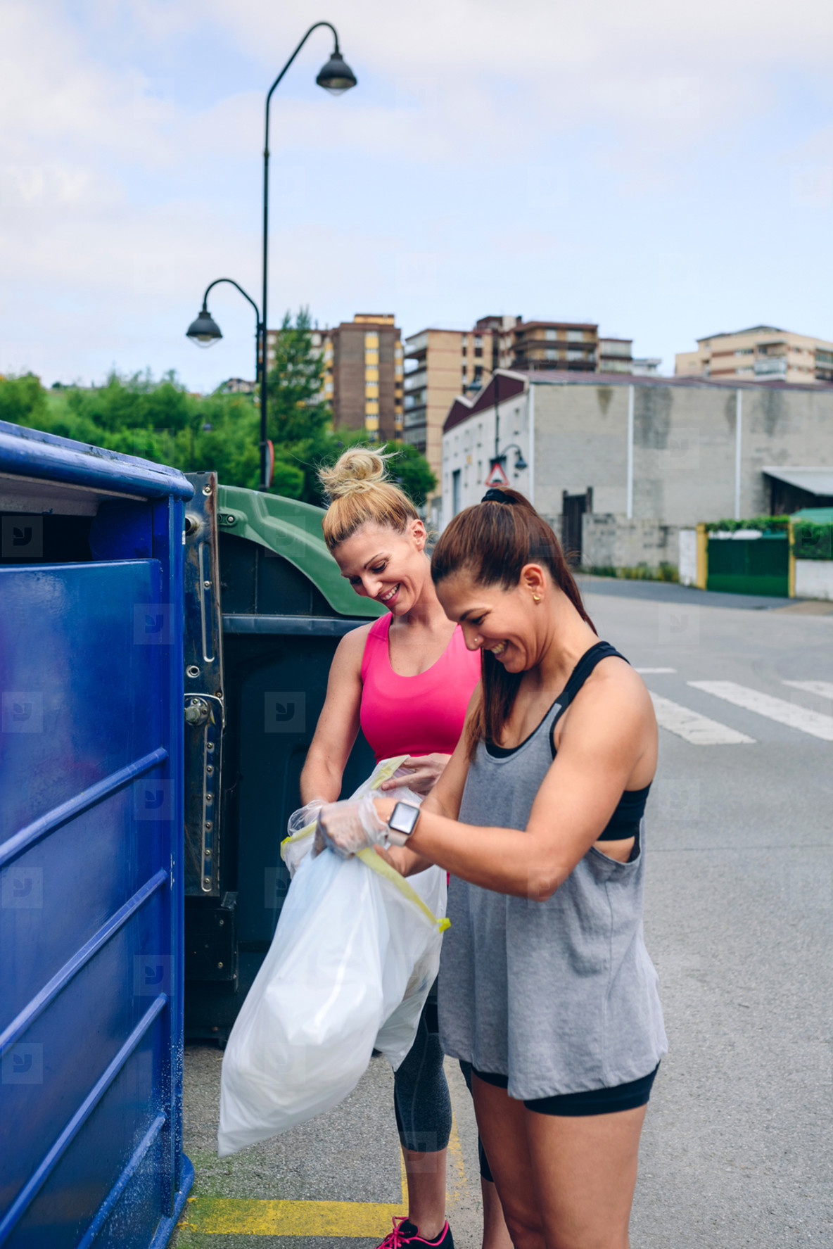 Girls throwing garbage to recycling dumpster
