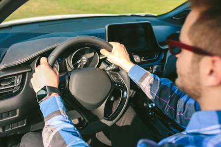 Young man holding steering wheel while driving the car