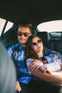 Young couple resting in the backseat of the car