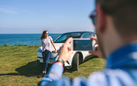 Guy taking picture of girl leaning on a car