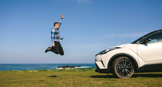 Young man jumping happy with car