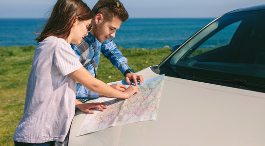 Couple looking at a map leaning on the car