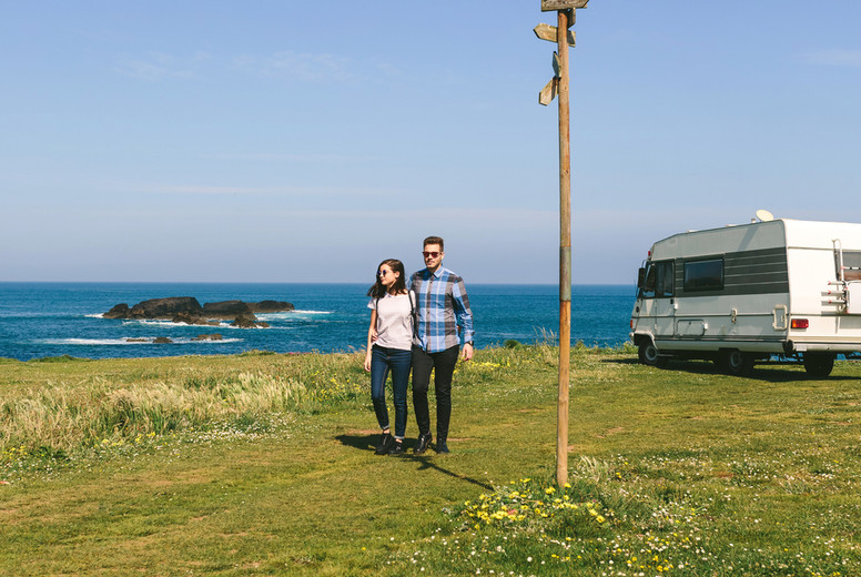 Couple taking a walk near the coast with a camper