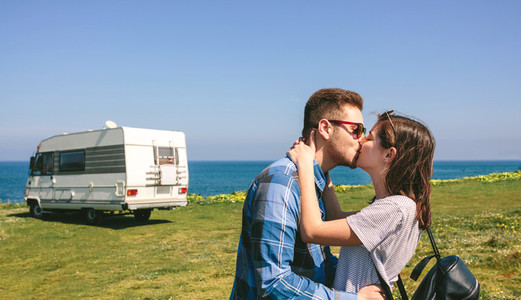 Couple kissing near the coast with a camper