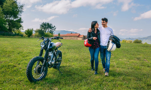 Couple walking on the field embraced and motorbike