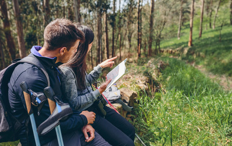 Couple doing trekking sitting looking at a map