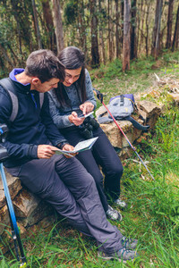 Couple doing trekking sitting looking mobile and map