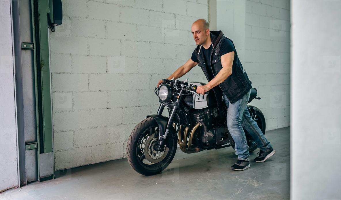 Man with custom motorbike leaving the garage