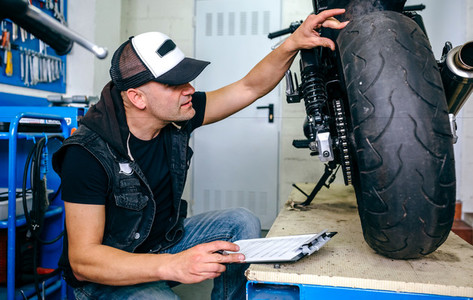 Mechanic checking wheel of a customized motorcycle