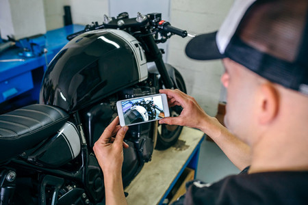 Mechanic taking picture of customized motorcycle
