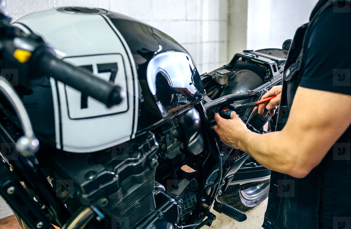 Motorcycle mechanic changing a fuse