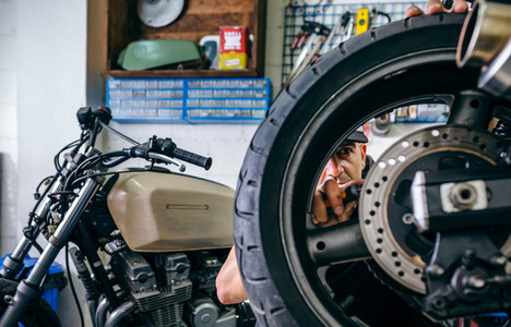 Mechanic fixing custom motorcycle wheel