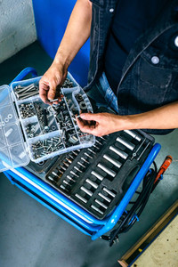 Mechanics hands choosing screws from a tool box