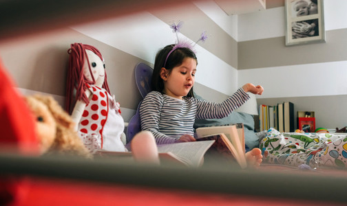 Girl disguised reading a book to her doll
