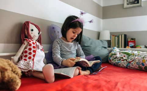 Girl disguised reading a book to her doll