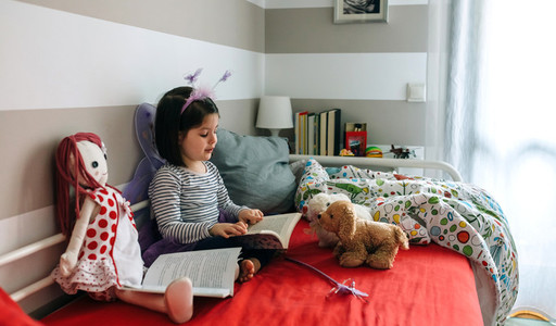 Girl disguised reading a book to her toys