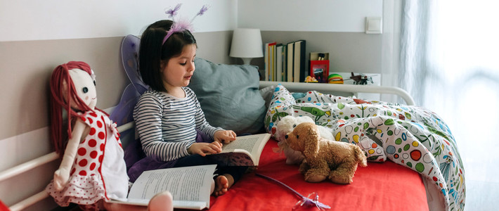 Girl disguised reading a book to her toys