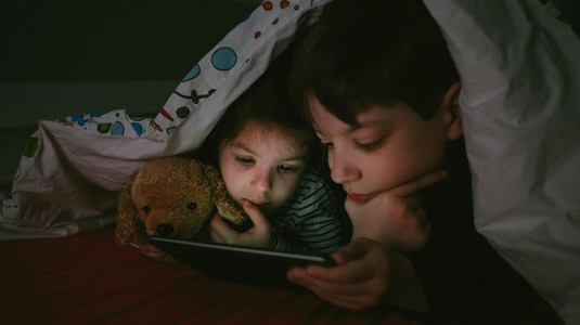 Brothers looking at the tablet in the dark