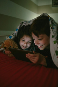 Brothers looking at the tablet in the dark