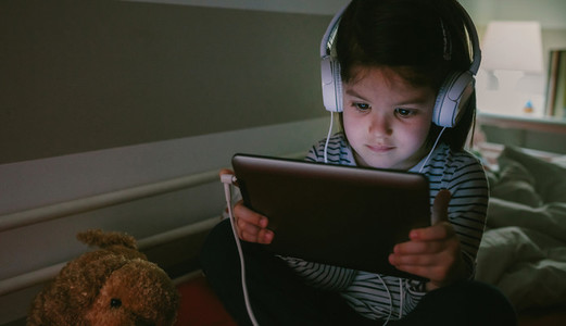 Girl with headphones looking at the tablet