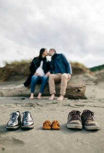 Family shoes in the sand with couple kissing