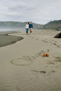 Parents walking with baby name Oliver written in the sand