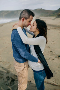 Pregnant woman hugging partner on the beach