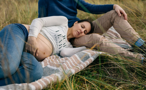 Pregnant sleeping on a blanket on the grass