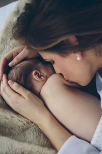 Mother kissing her newborn baby girl